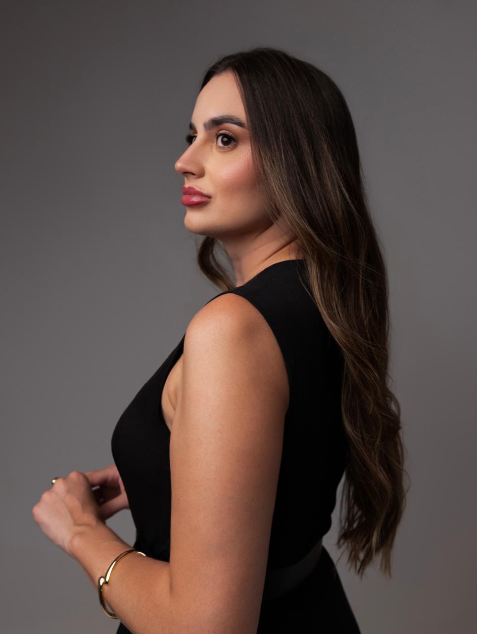 Nathalia Crestani de perfil, em fundo neutro de estúdio.